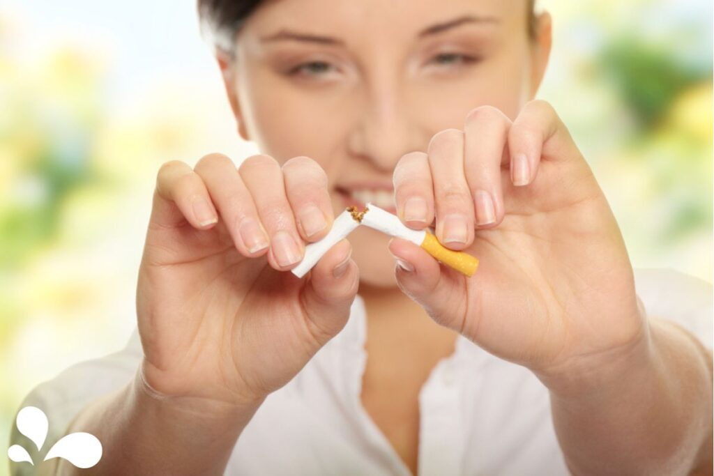 A woman breaking a cigarette in half, symbolizing a commitment to quitting smoking for a healthier lifestyle and pregnancy.