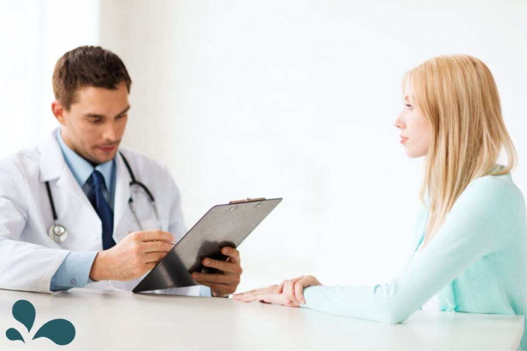 A woman in a clinical setting discussing her health with a primary care physician, with focus on prenatal care and consultation