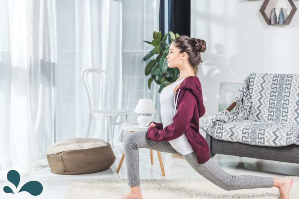 A focused woman in home attire performing a stretching exercise, promoting in-home fitness routines for expectant mothers.