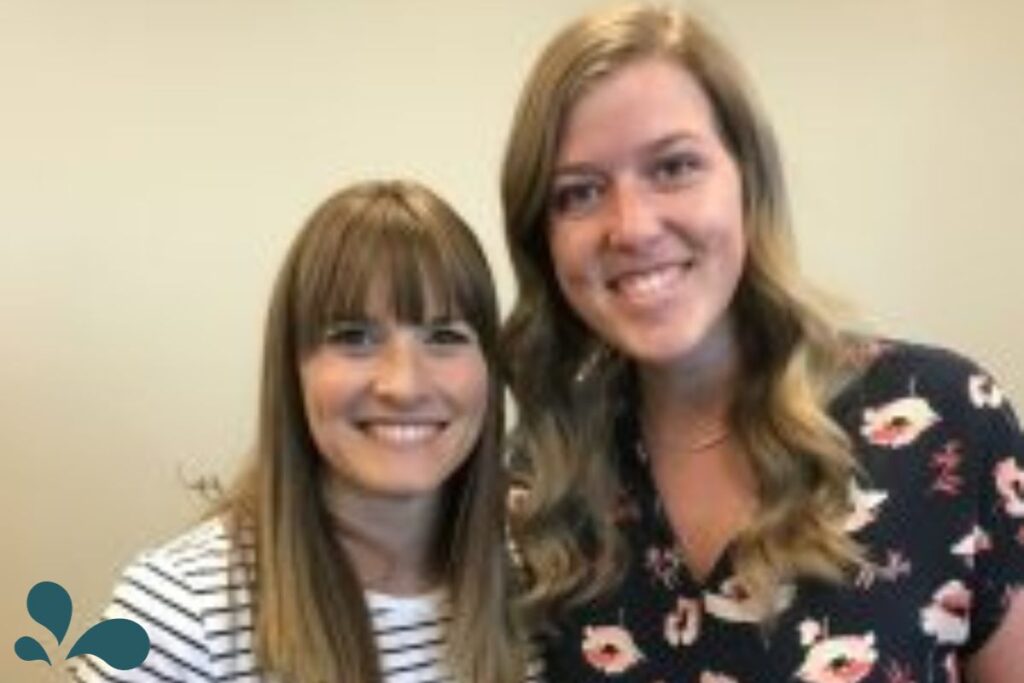 Two smiling women with medium-length hair posing together, one with a striped shirt and the other in a floral top.