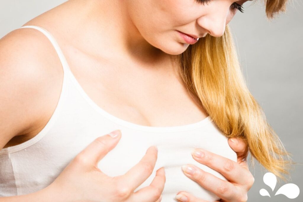 An image portraying a mother experiencing discomfort while holding her chest area, with a concerned expression. This visual represents common challenges some mothers face during breastfeeding and the need for proper guidance and care.