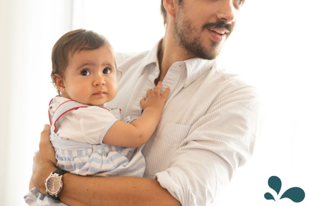 A father holding his infant child in a loving embrace, showcasing a supportive role in childcare.