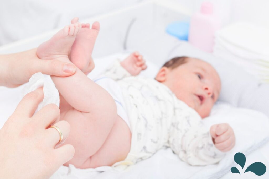 A parent's hands delicately holding a newborn's feet during a diaper change, with the baby resting comfortably on a changing table, surrounded by a serene nursery setting.