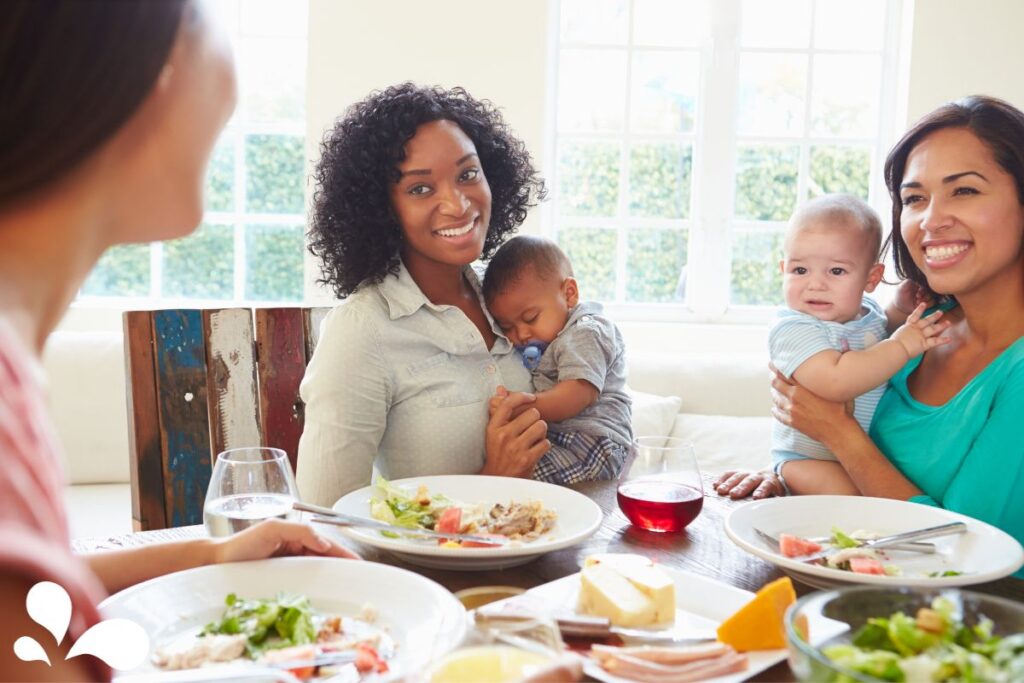 A group of friends enjoying lunch together with their babies, embodying a supportive community for parents.