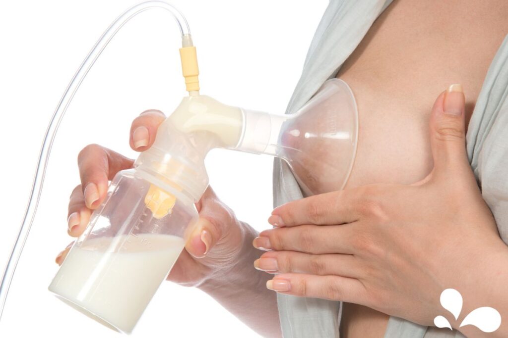 Close-up of a woman using a hands-on pumping technique, with a breast pump suctioned to her breast and milk flowing into a bottle, demonstrating an effective way to express breast milk.