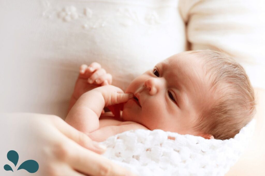 A serene newborn cradled gently in soft white blankets, with delicate fingers touching their face, embodying the innocence and peace of early life.