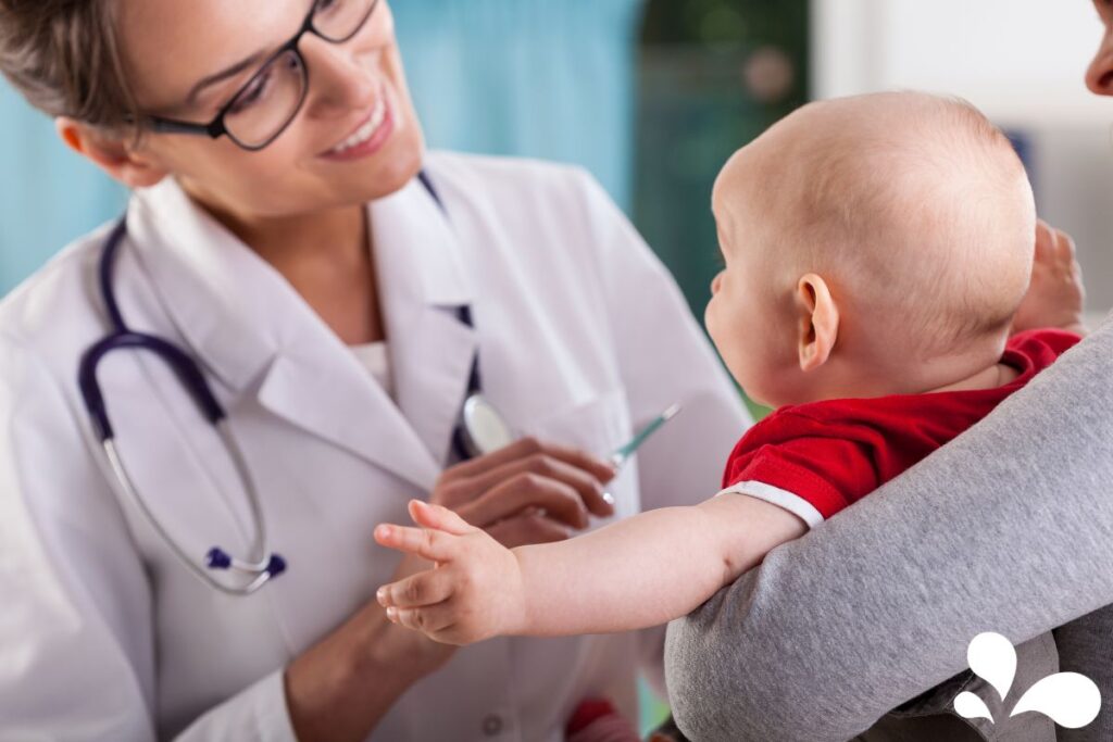 Pediatrician smiling at a baby while discussing care with the attentive mother.