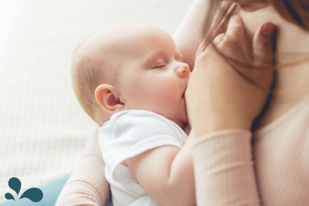 A gentle scene of a mother in a soft pink shirt breastfeeding her sleeping baby, showcasing the calm and loving act of nursing.