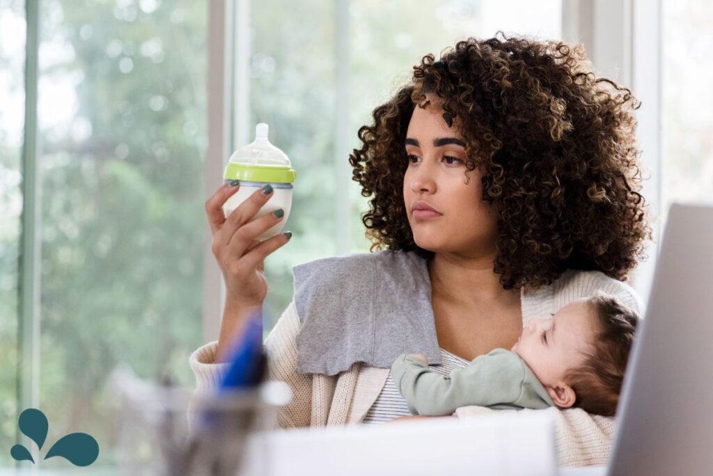 A mother sitting by a window, checking the amount of milk in a baby bottle, ensuring her baby's nutritional needs are met.