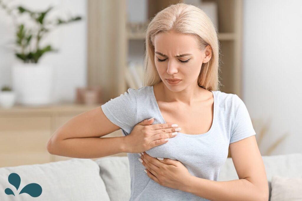 A woman in pain, holding her chest, depicting the discomfort of mastitis, emphasizing the need for awareness and proper care for breastfeeding mothers.