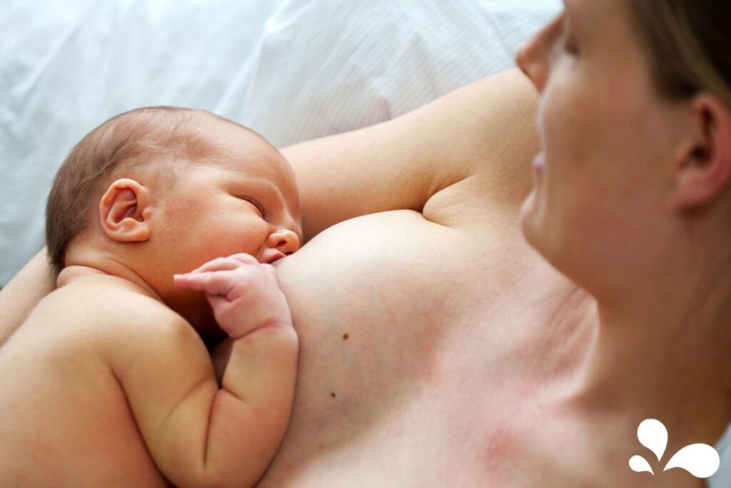 A newborn baby resting peacefully on its mother's chest, exhibiting the bonding practice of skin-to-skin contact. Both are relaxed and content.