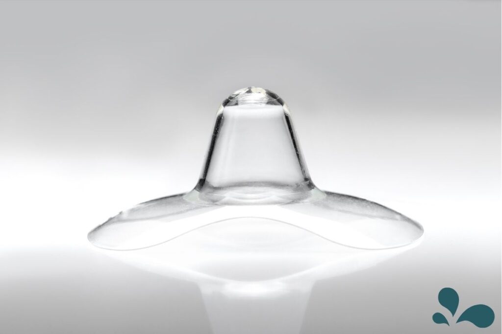 A close-up of a single, clear silicone nipple shield against a white background, highlighting its design and texture.