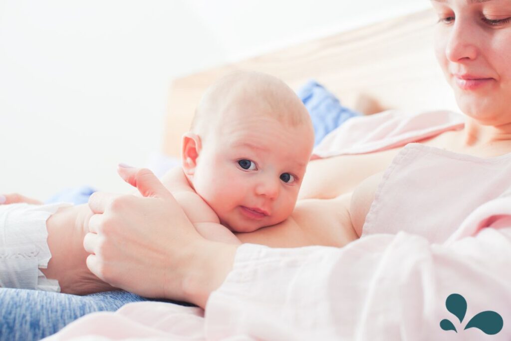 A new mama holding her new baby skin-to-skin in a bed at home.