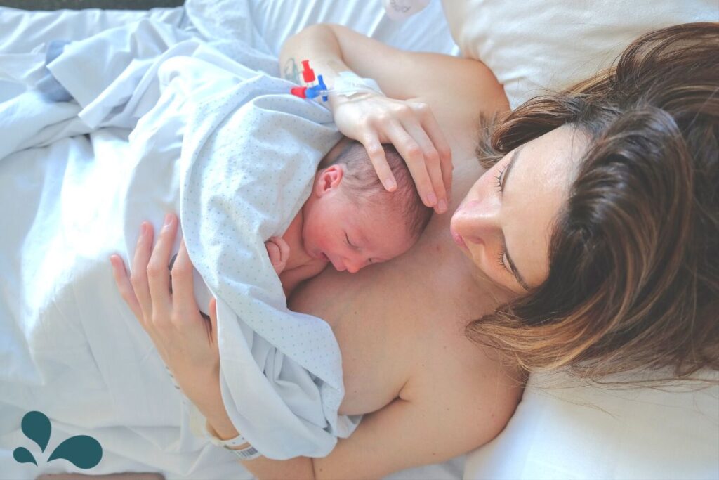 A new mama holding her new baby skin-to-skin in a hospital bed.